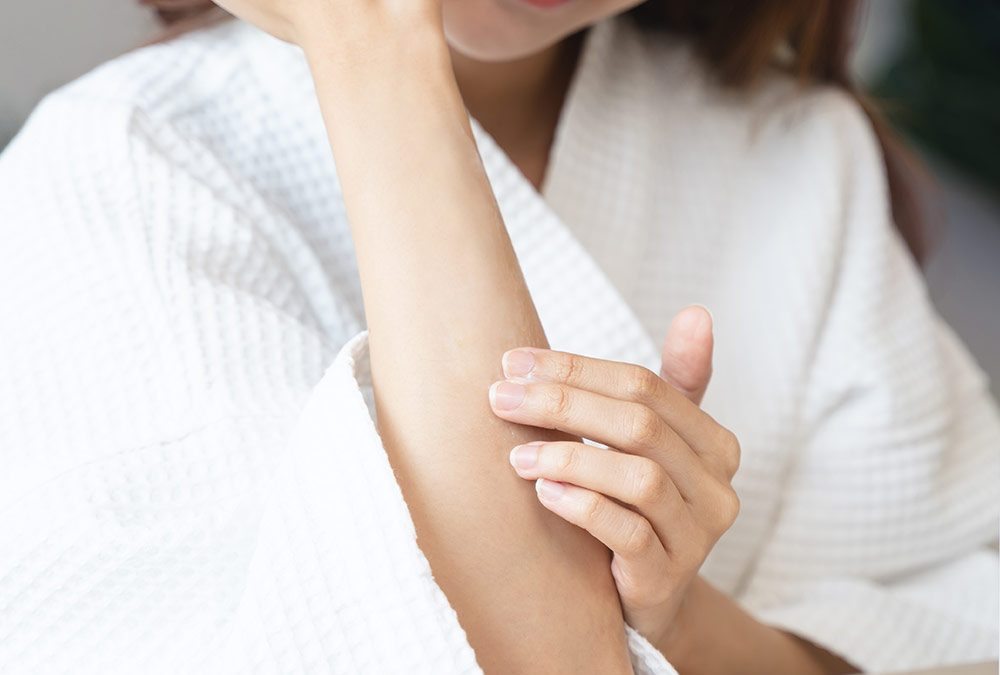 Woman in robe touching her arm: waxing for sensitive skin